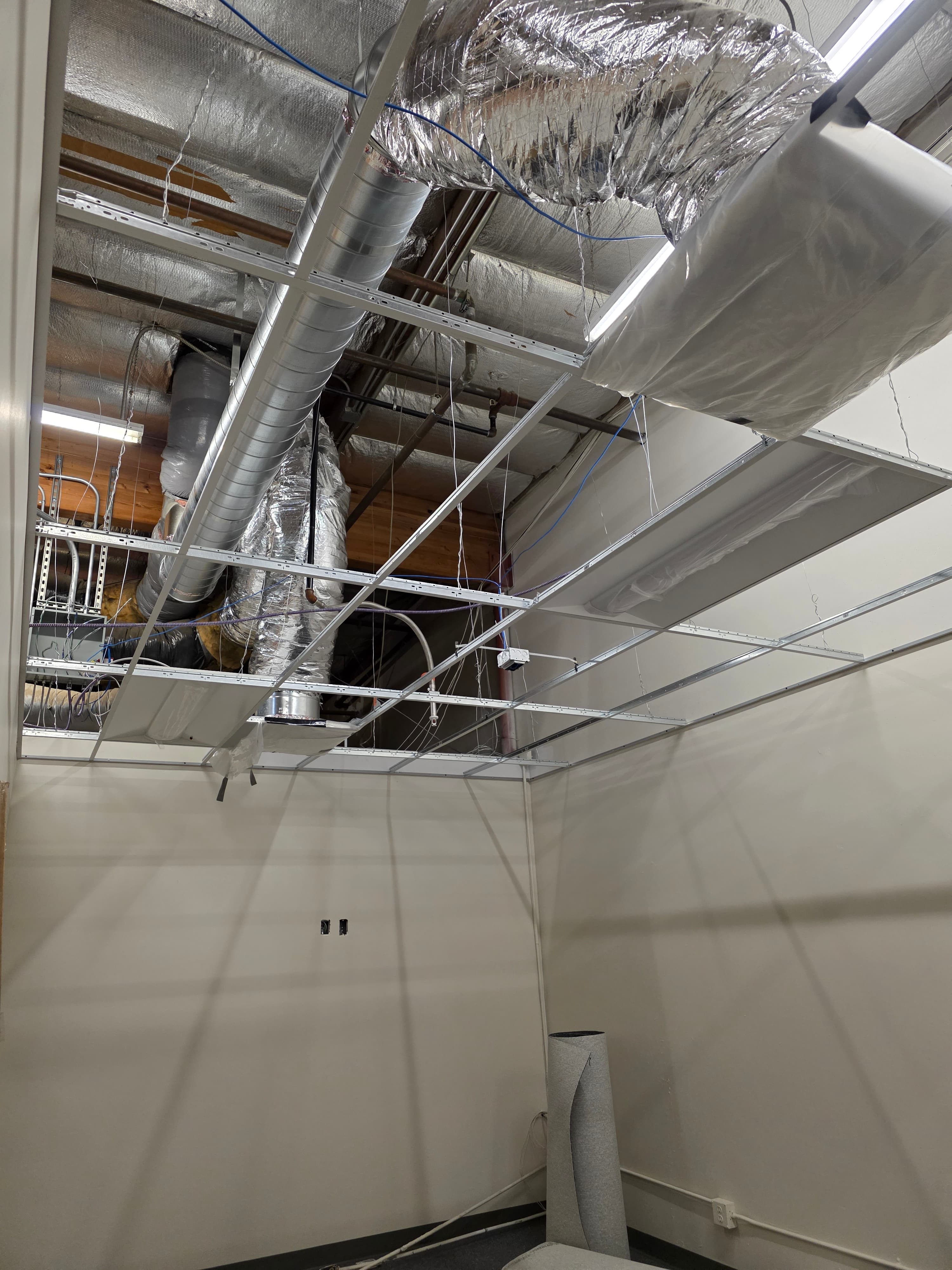 Commercial suspended ceiling grid with ductwork, conduit, and LED troffers
