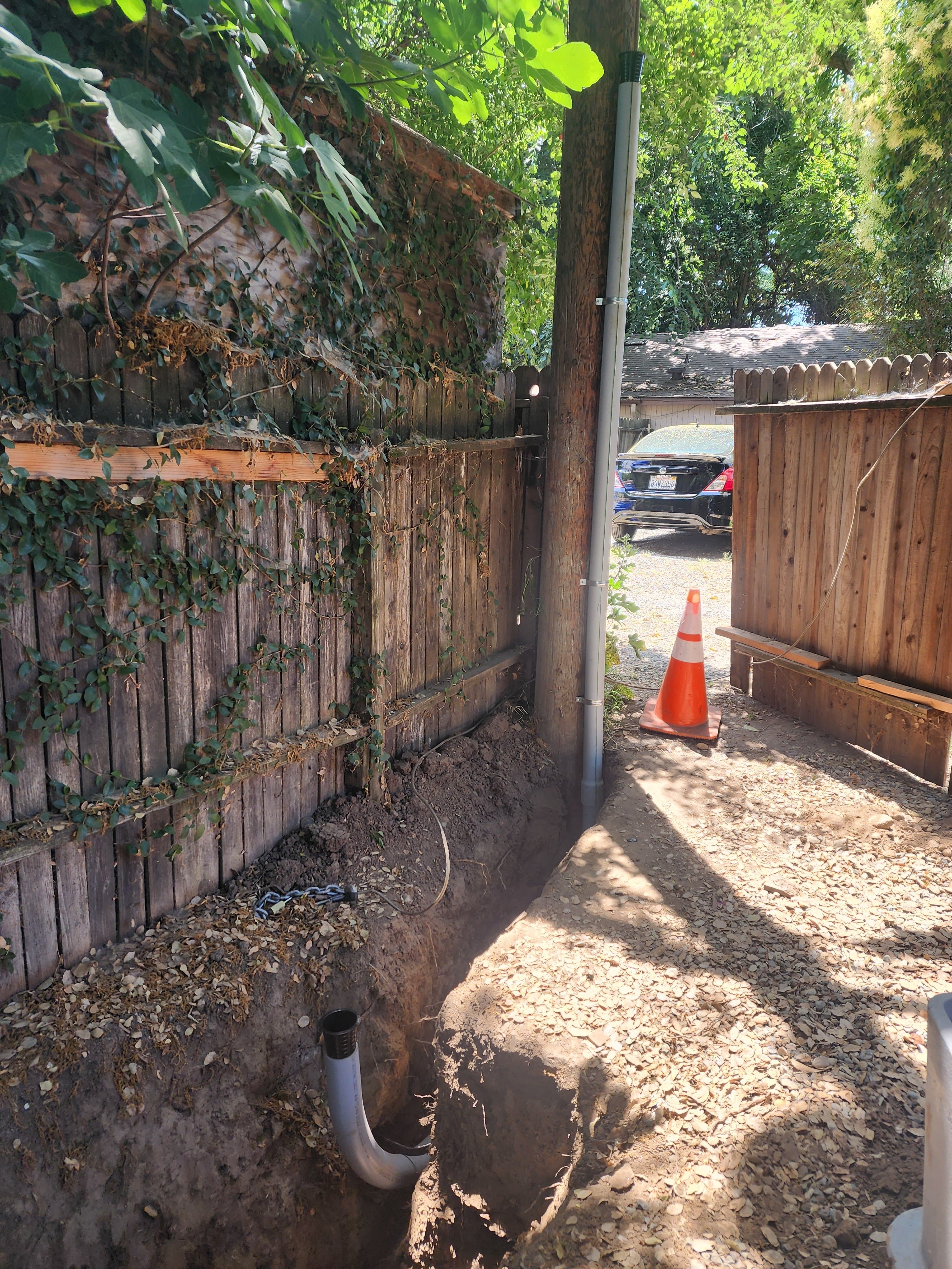 Trench with conduit riser and PVC sweep along a fence line