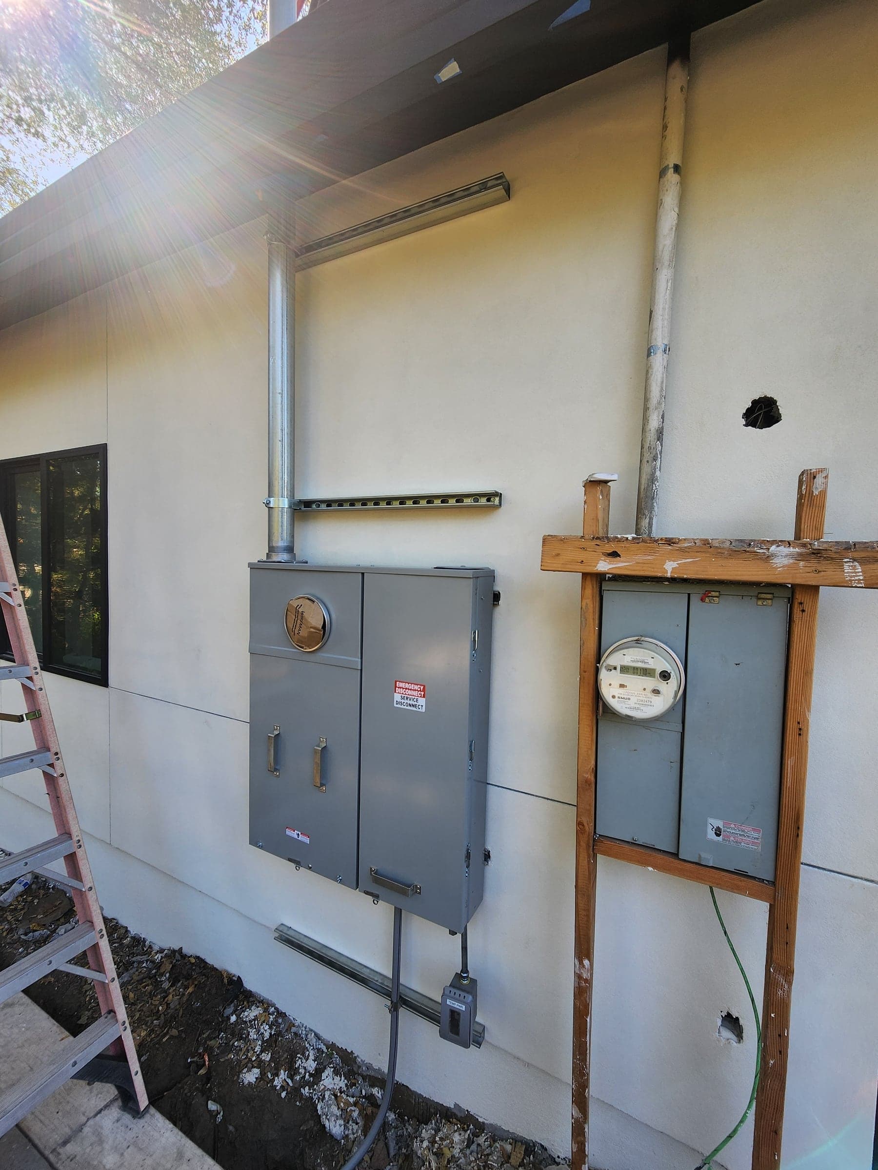 New exterior service disconnect and meter-main with a service mast beside an older utility meter in Sacramento, CA