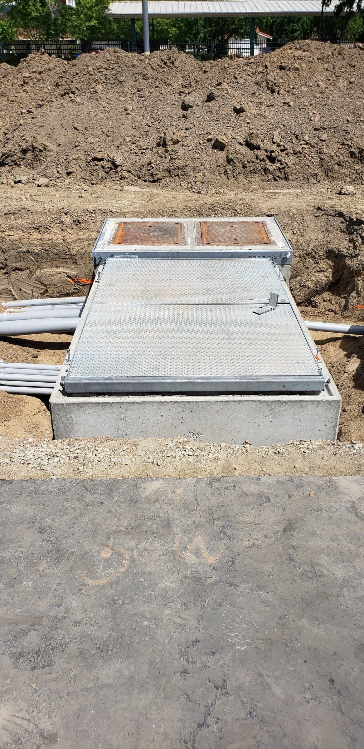 Racked PVC duct bank sweeping into a concrete underground pull vault at a commercial site in Roseville, CA